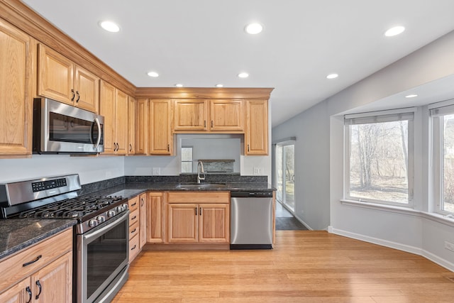 kitchen with light wood-type flooring, a sink, recessed lighting, stainless steel appliances, and dark stone counters