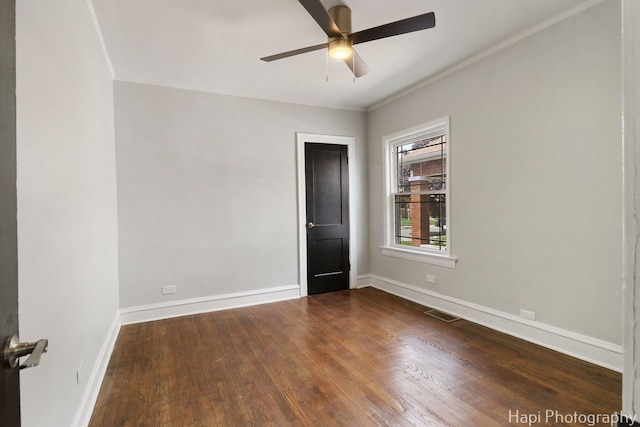 empty room featuring a ceiling fan, dark wood-style flooring, baseboards, and crown molding