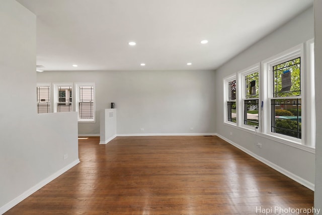 empty room featuring recessed lighting, baseboards, and dark wood-style flooring