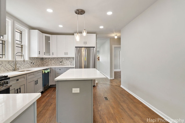 kitchen featuring a sink, stainless steel appliances, tasteful backsplash, dark wood finished floors, and baseboards