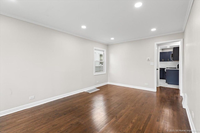 spare room featuring dark wood-style floors, visible vents, crown molding, and baseboards