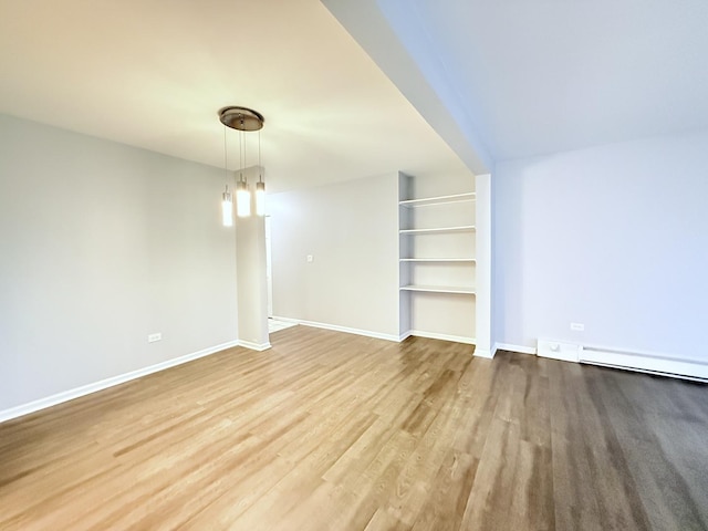 empty room featuring baseboard heating, baseboards, and wood finished floors