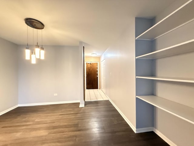 unfurnished dining area featuring baseboards and wood finished floors