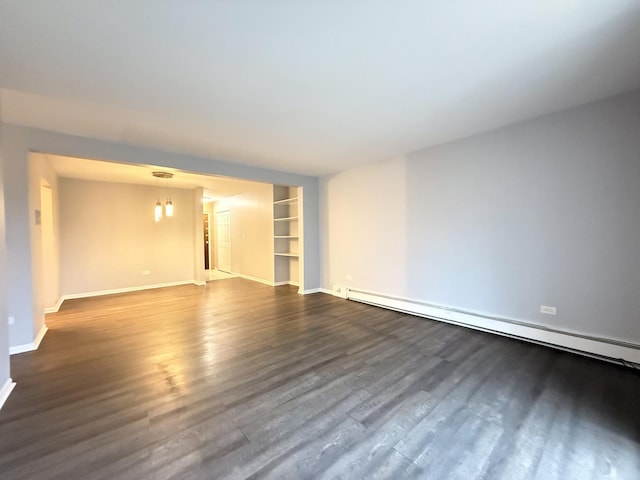 empty room with dark wood-type flooring, built in shelves, baseboards, and a baseboard radiator