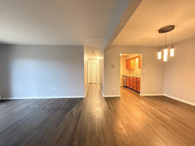 unfurnished living room featuring a sink, baseboards, and dark wood-style floors