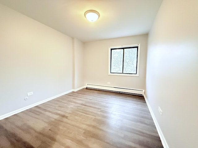 empty room with baseboards, baseboard heating, and wood finished floors