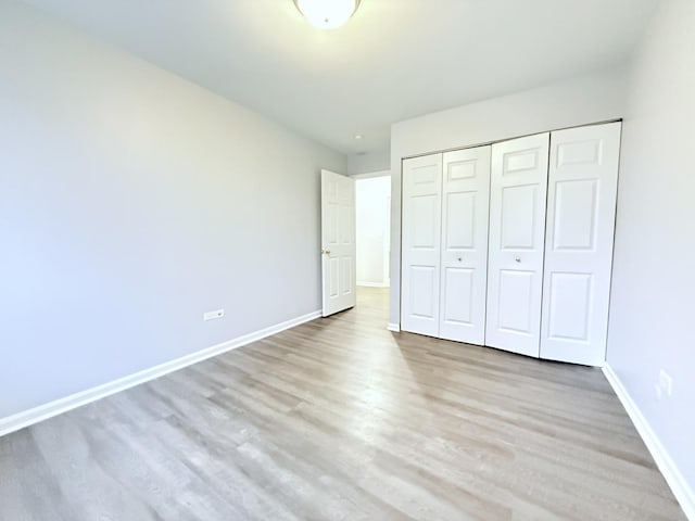 unfurnished bedroom with a closet, baseboards, and wood finished floors