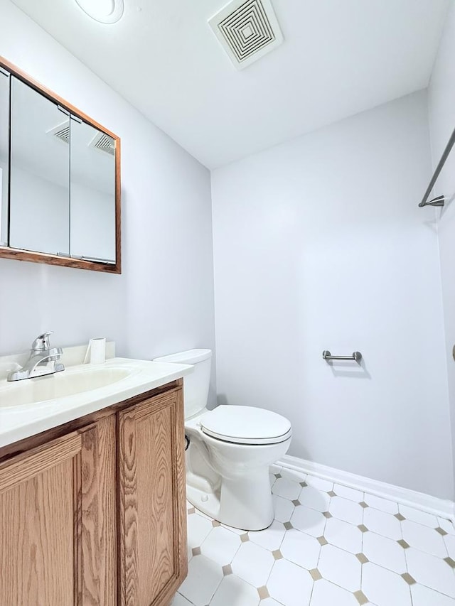 bathroom with vanity, toilet, baseboards, and visible vents