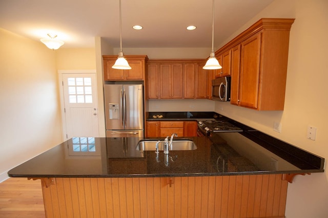 kitchen featuring a sink, brown cabinets, appliances with stainless steel finishes, and a peninsula