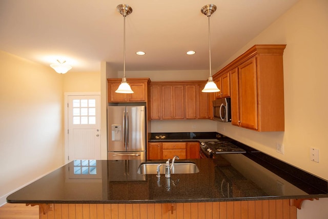 kitchen featuring brown cabinets, appliances with stainless steel finishes, a peninsula, and a sink