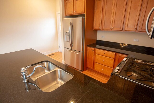 kitchen with dark countertops, brown cabinets, appliances with stainless steel finishes, and a sink