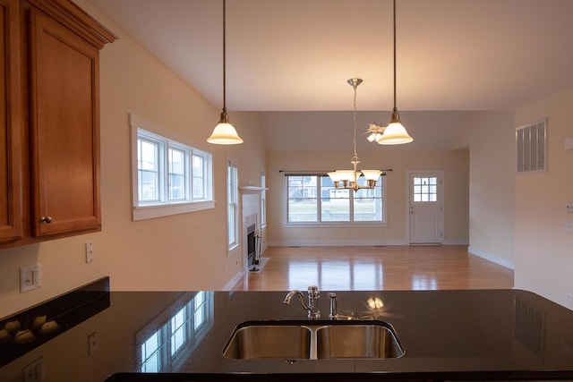 kitchen featuring brown cabinetry, visible vents, a chandelier, and a sink