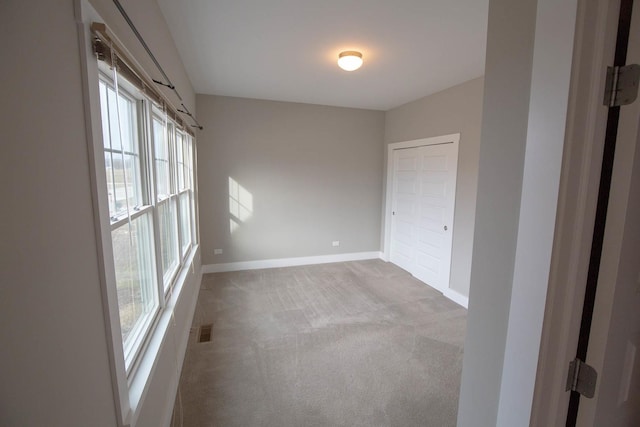 carpeted spare room with visible vents and baseboards