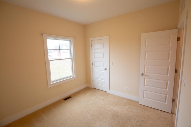 unfurnished bedroom featuring visible vents, baseboards, and light colored carpet