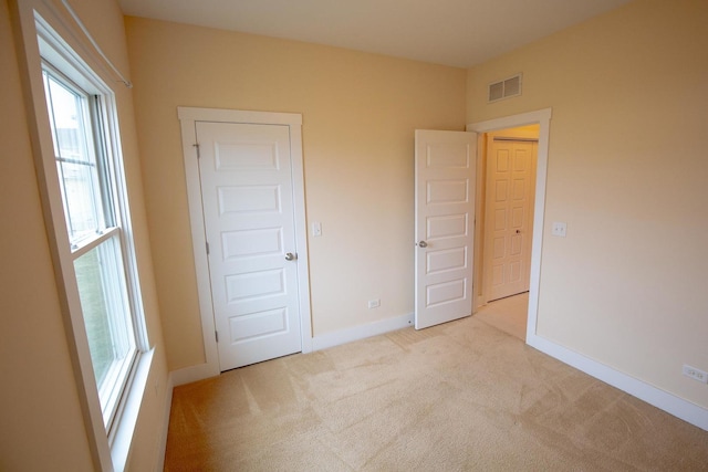 unfurnished bedroom featuring light carpet, visible vents, and baseboards