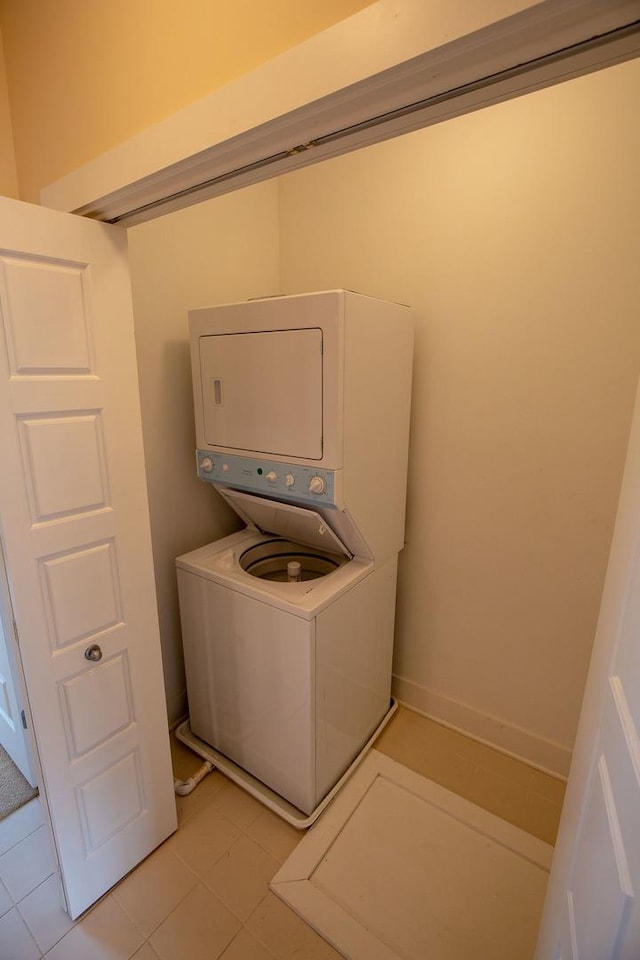 laundry area with stacked washer / drying machine, baseboards, and laundry area