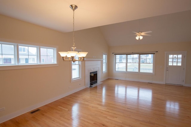 unfurnished living room with ceiling fan with notable chandelier, baseboards, light wood-type flooring, and lofted ceiling