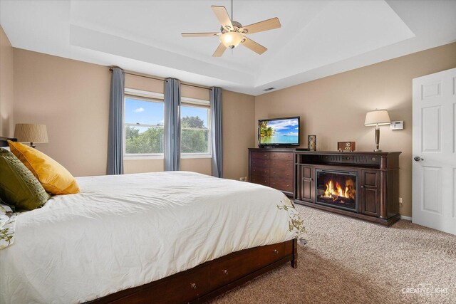 432 S Cherry St, Itasca, IL 60143 - carpeted bedroom with a tray ceiling, a glass covered fireplace, and a ceiling fan