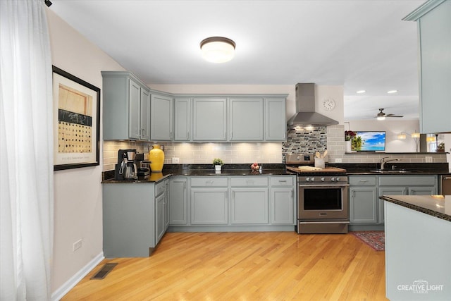 432 S Cherry St, Itasca, IL 60143 - kitchen featuring wall chimney exhaust hood, stainless steel range with gas stovetop, gray cabinetry, light wood-style floors, and backsplash