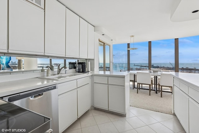 kitchen featuring a water view, dishwasher, light countertops, white cabinets, and a sink