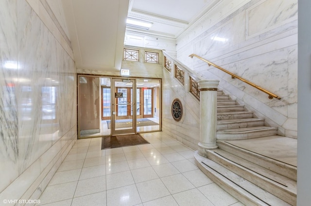 tiled entrance foyer featuring stairs, french doors, a towering ceiling, and crown molding