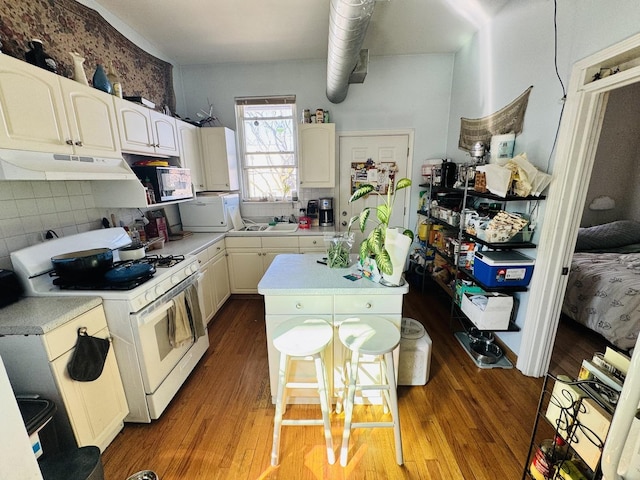 944 W 18th St, Chicago, IL 60608 - kitchen featuring white gas stove, under cabinet range hood, a center island, light countertops, and decorative backsplash