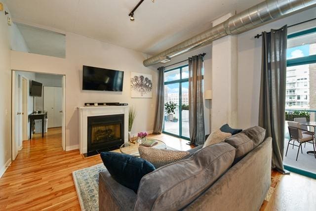 910 W Madison St Unit 501, Chicago, IL 60607 - living room with light wood-style floors, a fireplace with flush hearth, and rail lighting