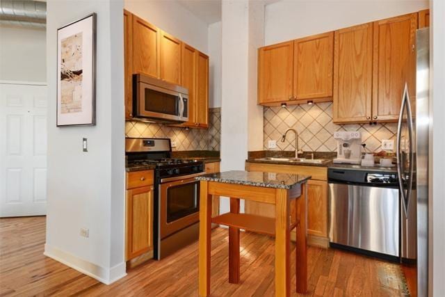 910 W Madison St Unit 501, Chicago, IL 60607 - kitchen with appliances with stainless steel finishes, light wood-style flooring, backsplash, and dark stone counters