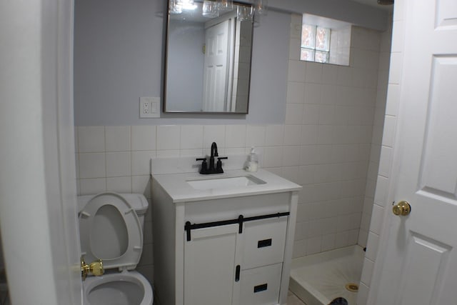 bathroom with vanity, tile walls, toilet, and a shower stall