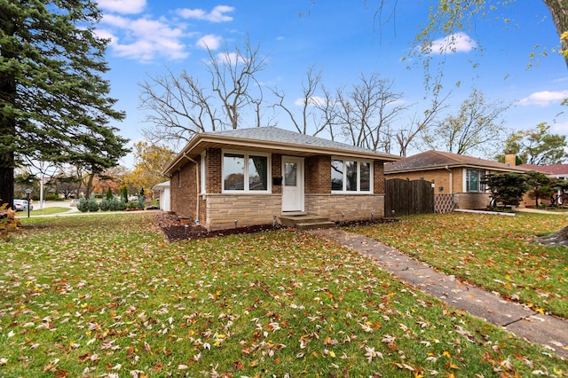 view of front of house featuring a front lawn, fence, brick siding, and stone siding