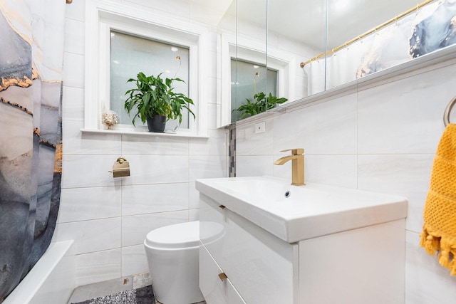 bathroom with toilet, tile walls, and vanity