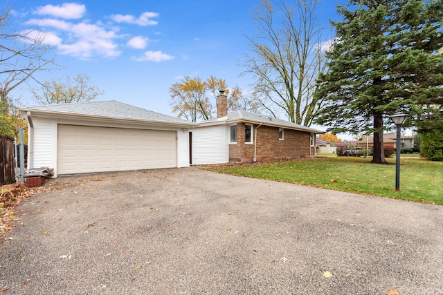 view of front facade with a front lawn, aphalt driveway, fence, an attached garage, and a chimney