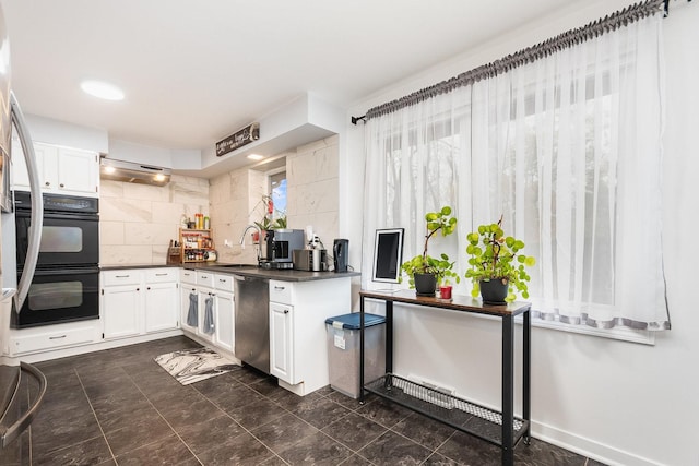 kitchen with white cabinetry, dobule oven black, stainless steel dishwasher, dark countertops, and tasteful backsplash