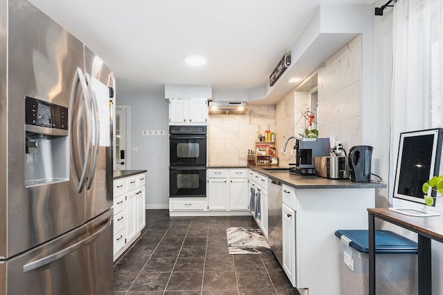 kitchen with dark countertops, under cabinet range hood, decorative backsplash, stainless steel appliances, and white cabinetry