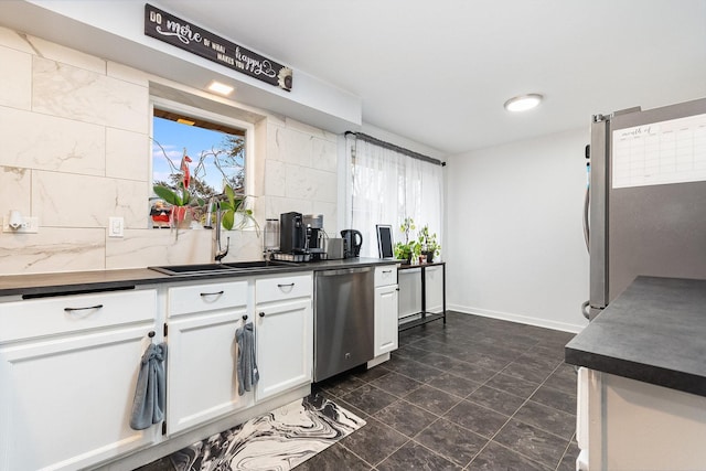 kitchen with dark countertops, white cabinetry, stainless steel appliances, and tasteful backsplash