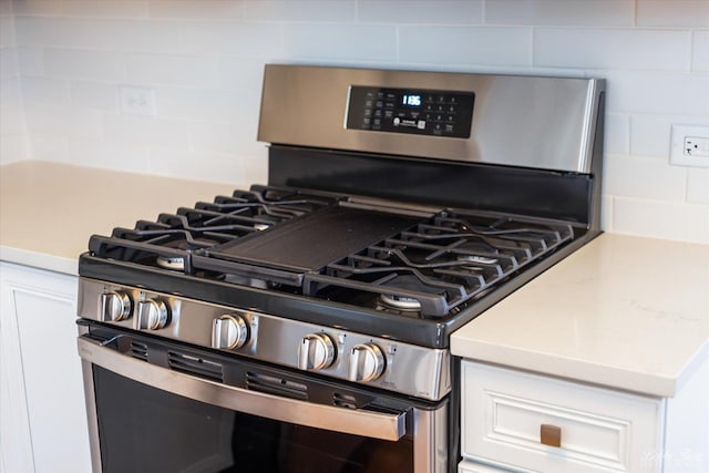 details featuring light countertops, white cabinets, tasteful backsplash, and stainless steel range with gas cooktop