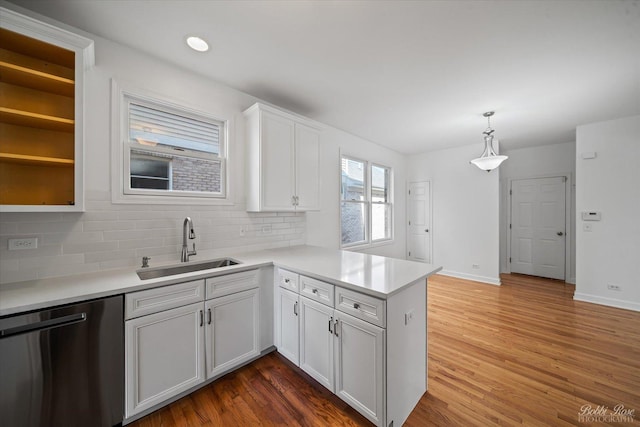 kitchen with dishwasher, wood finished floors, a peninsula, and a sink