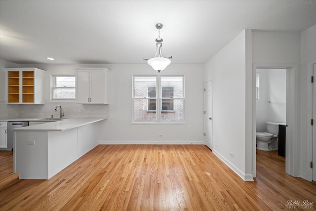 kitchen with light wood-style flooring, a sink, light countertops, white cabinets, and tasteful backsplash