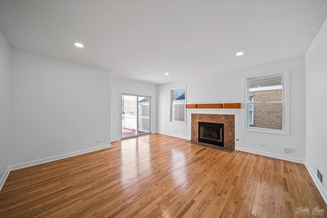 unfurnished living room with visible vents, recessed lighting, light wood-style floors, a fireplace, and baseboards