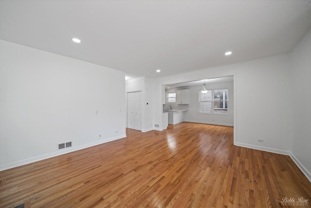 unfurnished living room with light wood finished floors, visible vents, recessed lighting, and baseboards