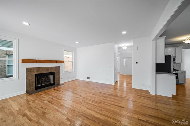 unfurnished living room with light wood finished floors, recessed lighting, a fireplace, and baseboards