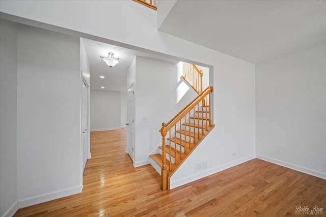 stairway with visible vents, baseboards, and wood finished floors