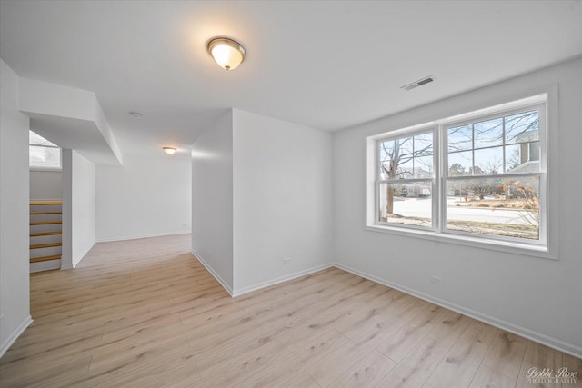 unfurnished room featuring stairs, baseboards, visible vents, and light wood finished floors