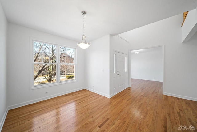 unfurnished dining area with baseboards and light wood finished floors