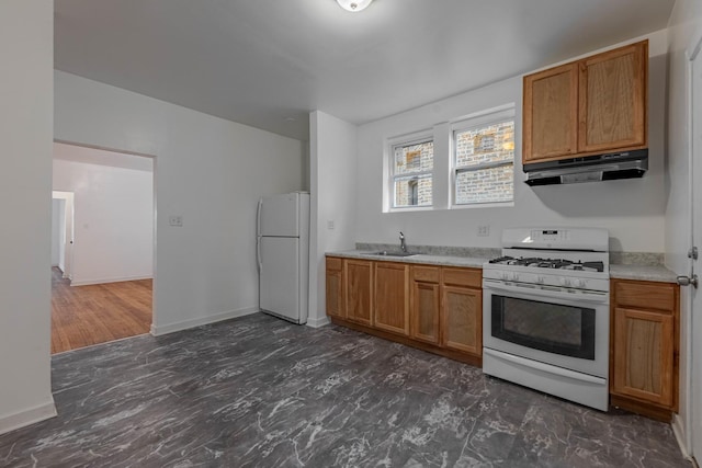 kitchen with baseboards, under cabinet range hood, light countertops, white appliances, and a sink