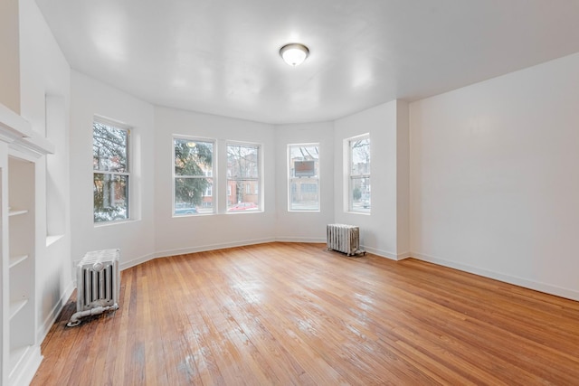 spare room with a wealth of natural light, light wood-style flooring, and radiator