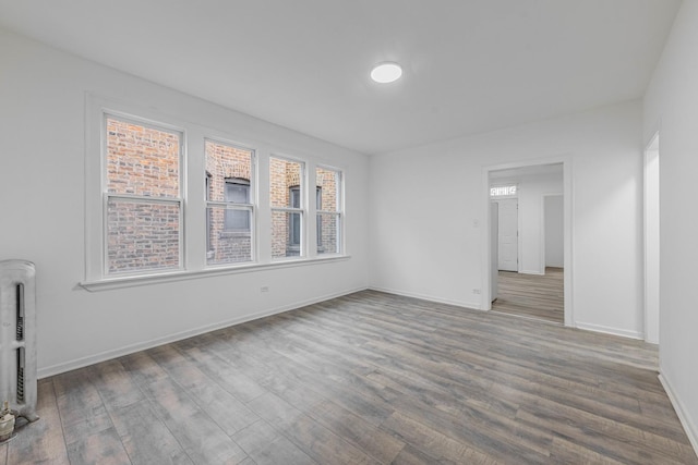 spare room featuring heating unit, wood finished floors, and baseboards