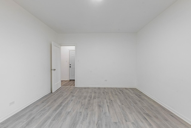 spare room with baseboards and light wood-type flooring