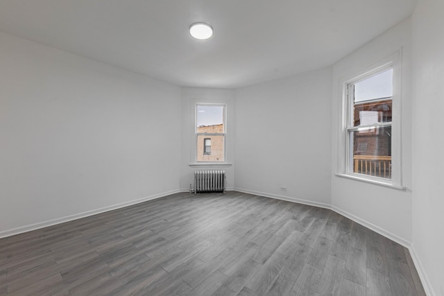 empty room featuring baseboards, radiator, and dark wood-style floors