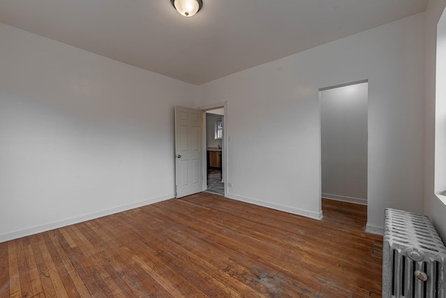 empty room with radiator, baseboards, and hardwood / wood-style floors